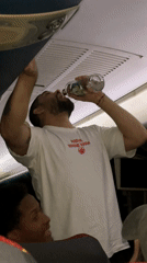 Airline passenger drinks from glass bottle during flight