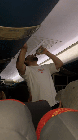 Airline passenger drinks from glass bottle during flight
