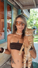 Woman holds ginger cat on house porch