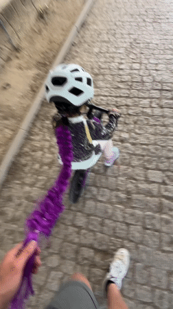 Child with purple hair extension rides bicycle in Vila Real