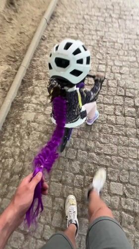 Child with purple hair extension rides bicycle in Vila Real