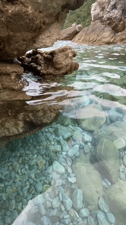 Woman sits by turquoise waters on Montenegro shore