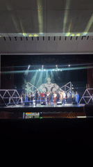 Stage performance with geometric decorations and crown centerpiece observed