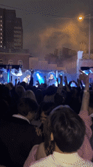 Nighttime outdoor concert with crowd recording performance
