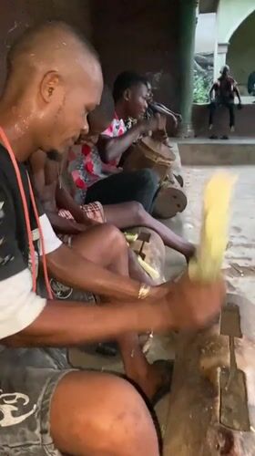Men gather for traditional sugar cane processing and drumming in Nigeria
