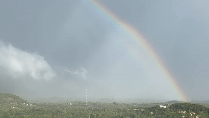 Rainbow appears over Koh Phangan forests during overcast conditions