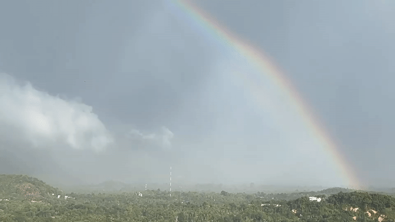 Rainbow appears over Koh Phangan forests during overcast conditions