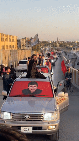 Political vehicle convoy rolls through central Quetta with portraits on display