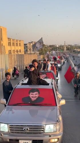 Political vehicle convoy rolls through central Quetta with portraits on display