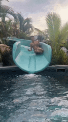 Person enjoys water slide at Thai swimming pool