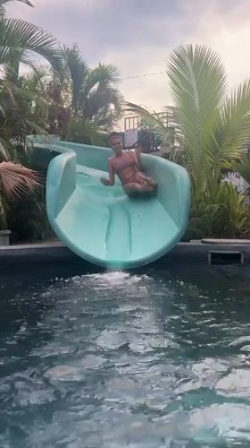 Person enjoys water slide at Thai swimming pool