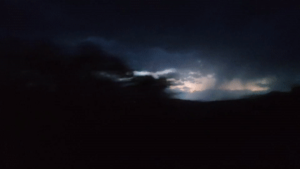 Lightning storm unfolds across a dark landscape at night