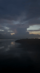 Children play on Indonesian beach during overcast morning