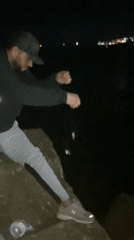 Person throws object into water from rocks in Tangier