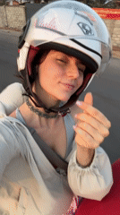 Woman on red scooter makes heart gesture in Mũi Né