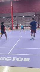 Badminton doubles match captured on indoor purple court