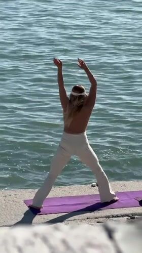 Woman practices yoga by water in Sirius, Russia