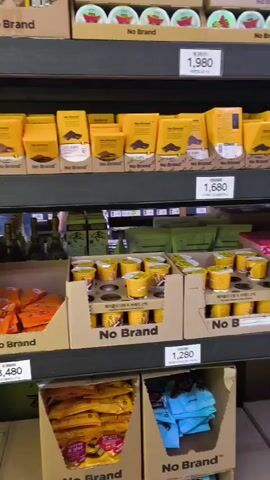 The video shows a person's arm reaching for a bottle of drink on a shelf in a store. The shelves are stocked with various food and beverage items, including snacks, drinks, and boxed goods. The store appears to be a discount or supermarket-style store, with price tags visible on some of the products. The lighting is bright and the overall atmosphere is typical of a retail environment.
