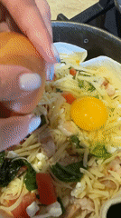 Person cracks eggs into cooking pan in Chaikovsky