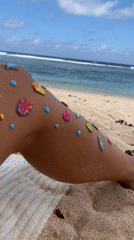 Beachgoer decorates legs with sea-themed stickers in Kuta Selatan