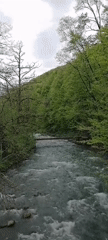 Rural Russian village and rushing river documented under overcast skies