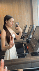 Woman takes gym selfie making peace sign near treadmill
