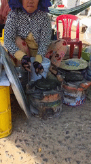 Woman cooks pancakes at bustling Vietnamese fruit market