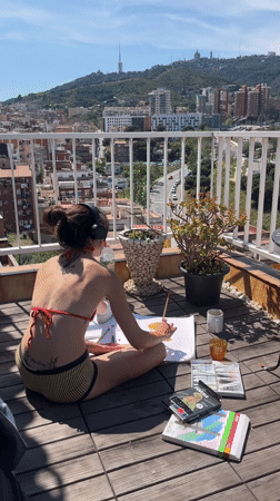 Woman paints on Barcelona balcony overlooking city panorama