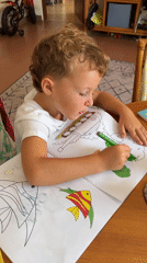 Young boy coloring with green marker in Kuta Selatan