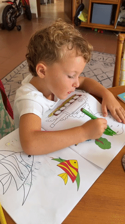 Young boy coloring with green marker in Kuta Selatan