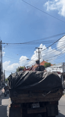 Three passengers ride in truck bed through Ubud streets