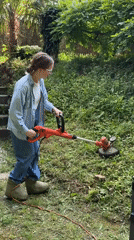Woman performs lawn maintenance with string trimmer in Erba