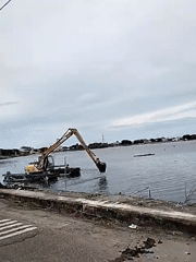 Children watch dredging operations in Lhokseumawe waterway
