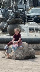 Child plays near fountain while woman takes selfie in Dmitrov