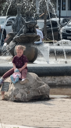 Child plays near fountain while woman takes selfie in Dmitrov