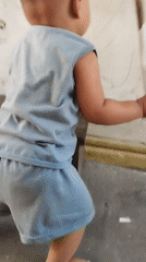 Toddler plays with broom in Surabaya residential alley