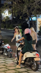 Three women gather around white moped in North Kuta