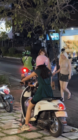 Three women gather around white moped in North Kuta