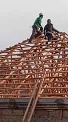Construction workers build wooden roof frame in Nigerian village