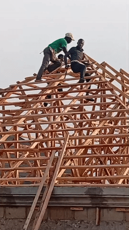 Construction workers build wooden roof frame in Nigerian village