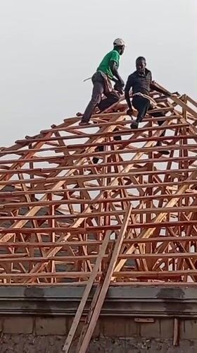 Construction workers build wooden roof frame in Nigerian village