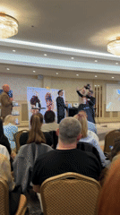 Indoor events include speech to audience, woman receives haircut