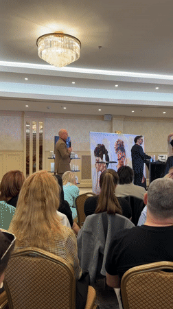 Indoor events include speech to audience, woman receives haircut