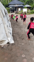 Children play soccer in Indonesian schoolyard wearing matching uniforms