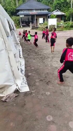 Children play soccer in Indonesian schoolyard wearing matching uniforms