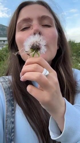 Woman blows dandelion seeds in Montenegro park moment