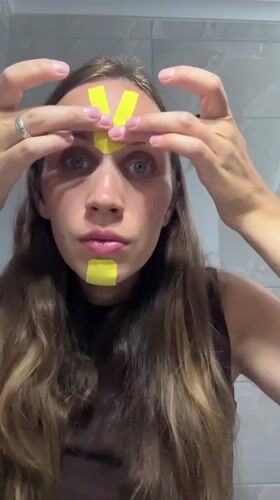 Woman applies kinesiology tape to face in Fethiye bathroom