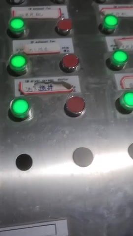 The video shows a control panel with multiple green and red buttons, some with Chinese labels. Below the buttons, a screen displays data in Chinese and numbers, with mostly green highlighting. The screen seems to show real-time operational information.