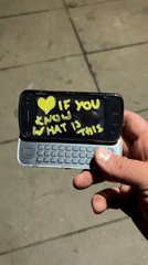 Person displays vintage Nokia N97 with graffiti message