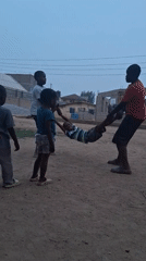 Children play swinging game on dirt road in Nigeria